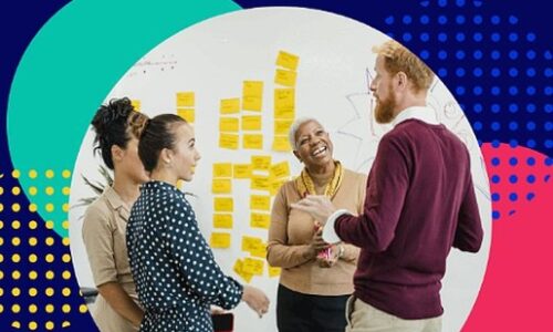 Pobl yn trafod mewn grŵp, yn sefyll wrth ymyl nodiadau Post-it ar y wal. People discussing in a group, standing next to post-it notes on the wall