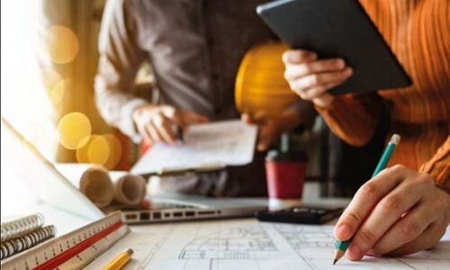 Agoslun o law yn dal pensil ac yn llunio cynlluniau. Close up of a hand holding a pencil and drawing plans