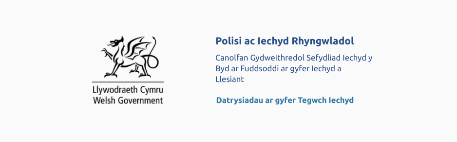 Cynllun bras o ddraig ar ben testun Llywodraeth Cymru yn eistedd i'r chwith o'r testun ar gyfer Cyfarwyddiaeth Polisi a Iechyd Rhyngwladol, a Canolfan Gydweithredol Sefydliad Iechyd Byd.